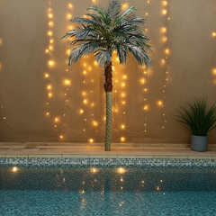 70 inch Artificial Silk Phoenix Palm Tree is in a pool setting highlighted by mini lights