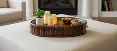 Set of 3 Oval Bamboo Serving Trays with Brass Rings holding candles, mini lights and nuts on a ottoman