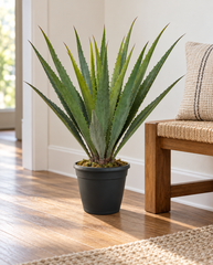 42 inch artificial PVC Agave in an included black pot on the floor beside a low bench in a minimalist home hallway