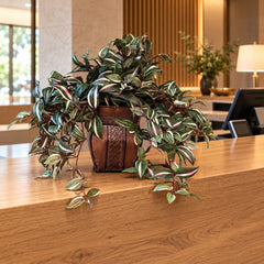 Artificial Wandering Jew ivy arrangement in its two-tone brown metal container on a boutique hotel reception counter.
