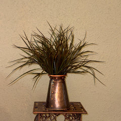 Original photograph of the 21-inch artificial sage green and brown grass arrangement in its riveted copper-tone container; display stand not included.