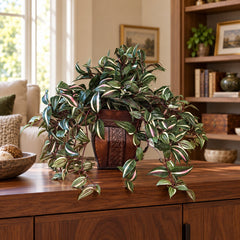 Artificial Wandering Jew ivy arrangement in its two-tone brown metal container on a walnut console in a home den.
